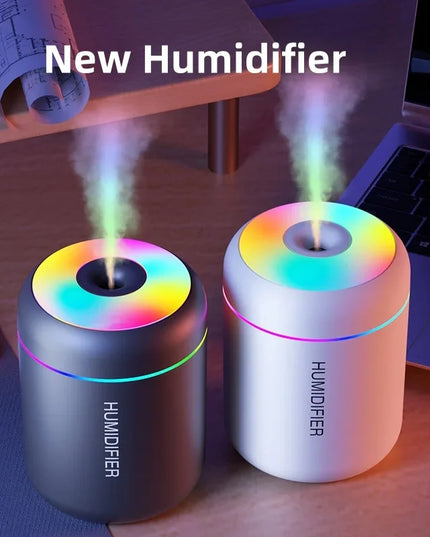 Two colorful humidifiers on a desk with a laptop and mouse in the background.
