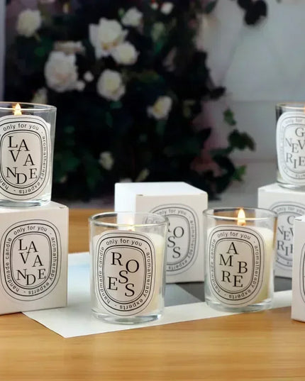 Scented lettered candles on a wooden dining table with Christmas tree background 