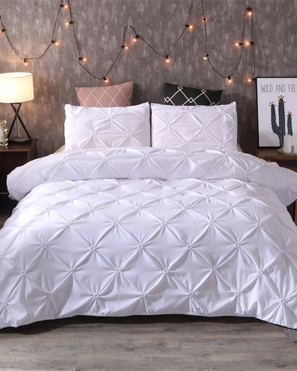 White quilted comforter set on a bed with decorative string lights and nightstands.