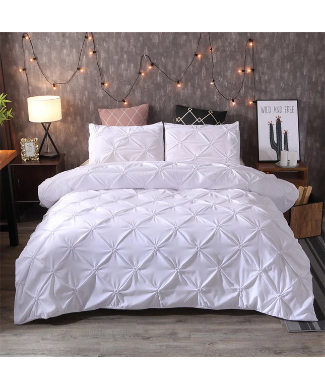 White quilted comforter set on a bed with decorative string lights and nightstands.