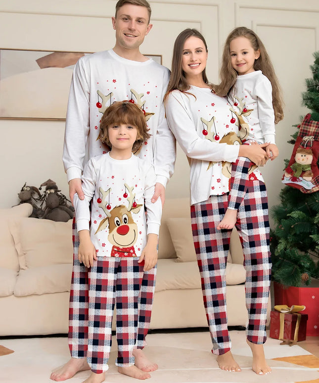 Family of four wearing matching Christmas pajamas in a living room setting.