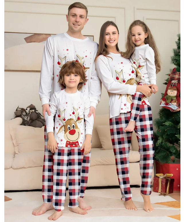 Family of four wearing matching Christmas pajamas in a living room setting.