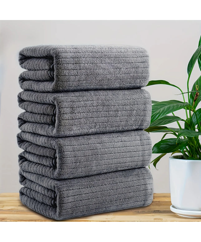 Stack of gray towels on a wooden surface with a plant in the background