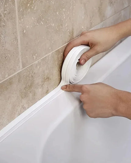 Person applying white caulk to a bathroom corner.