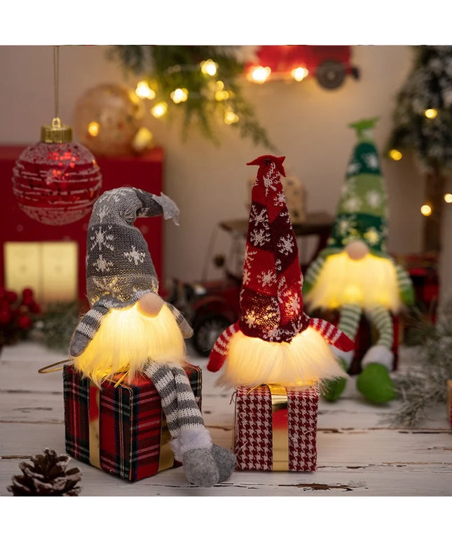 Decorative gnomes with lights on small gift boxes in a festive setting with Christmas trees and ornaments.