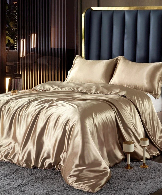 Beige satin bedding set on a bed with a dark upholstered headboard in a bedroom setting.