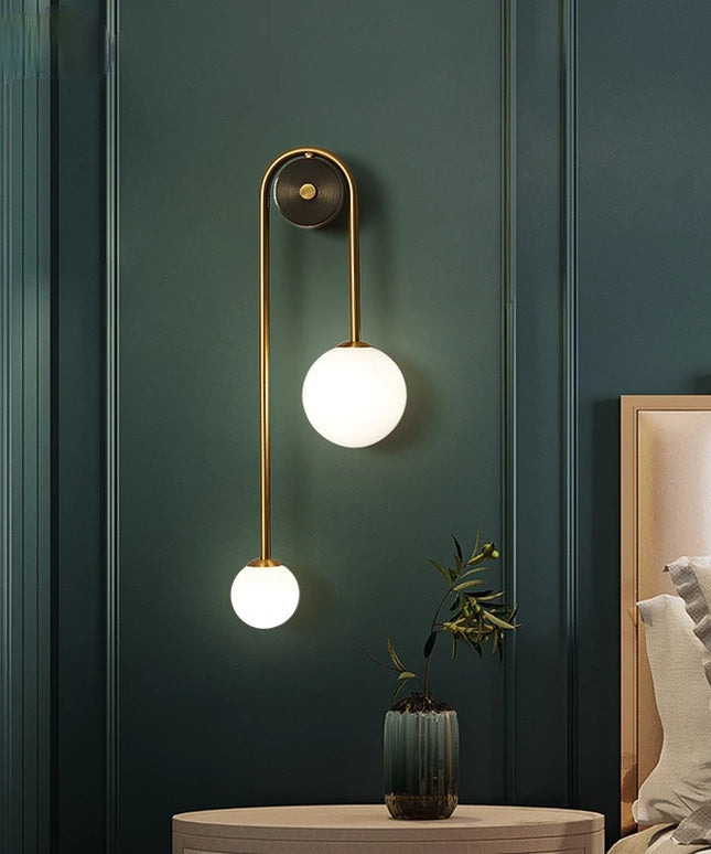 Modern wall lamp with two round lights on a dark green wall.