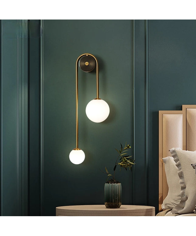 Modern wall lamp with two round lights on a dark green wall.