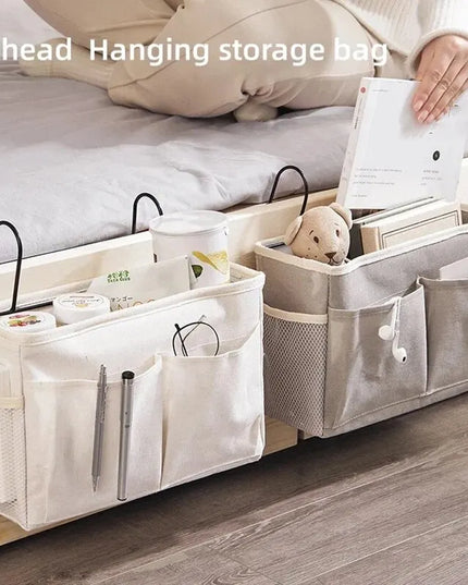 Bedhead hanging storage bag with various items on a bed